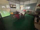 des tables et des chaises dans une pièce au sol vert et dotée d'une fenêtre