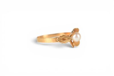 a close up of a gold ring with a pearl in the middle