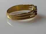 a gold ring on a white surface with a diamond in the middle