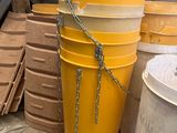 un grand seau jaune posé à côté d'une pile d'autres seaux
