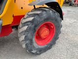 a yellow tractor with red wheels parked in a parking lot