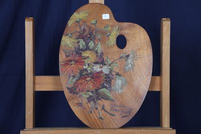 un chevalet en bois sur lequel est peinte une composition florale