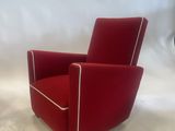 pair of red lounge chairs with white piping on the arms