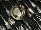 de nombreuses cuillères et fourchettes en argent posées sur une table noire