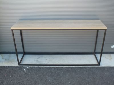 La table est en bois et en métal, avec un piètement noir.