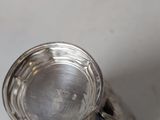 a silver cup with a handle on a white table