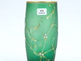 un vase vert orné de motifs dorés sur fond blanc