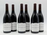 six bouteilles de vin sont alignées sur une surface blanche