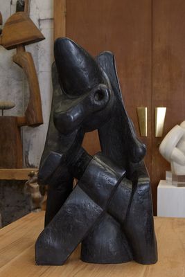 une sculpture noire posée sur une table en bois dans une pièce
