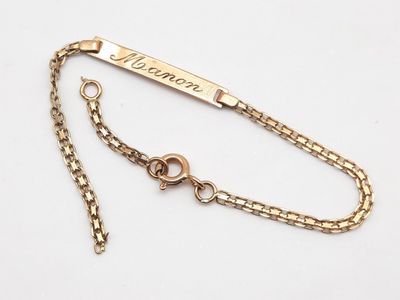 un gros plan sur un bracelet à chaîne en or orné d'une plaque portant un nom