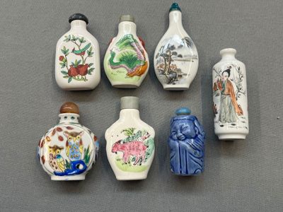 six petits vases aux motifs variés, posés sur une table