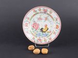 une assiette sur laquelle est représenté un coq, à côté de noix