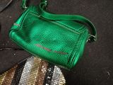 a green purse sitting on a black surface next to a pair of scissors