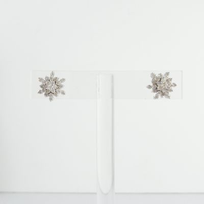 boucles d'oreilles clous en forme de flocon de neige en cristal, présentées sur un socle en acrylique transparent