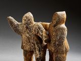 two figurines of people standing next to each other on a gray surface