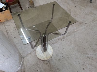 une table en verre avec une base en métal et un plateau en verre