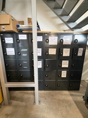 Plusieurs casiers métalliques sont alignés dans une pièce où se trouvent des cartons