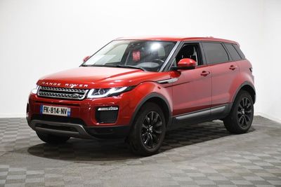 Une Land Rover rouge est garée sur un sol à damier.