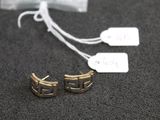 two pairs of gold earrings with tags on them on a table