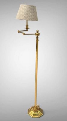 a gold floor lamp with a white shade on top of it