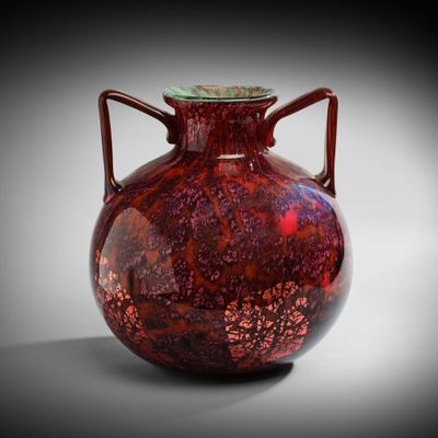 un vase rouge avec un couvercle vert posé sur une table