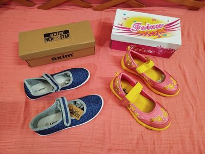 trois paires de chaussures et une boîte posées sur un lit