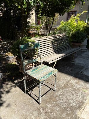 a wooden bench sitting on the sidewalk next to a chair