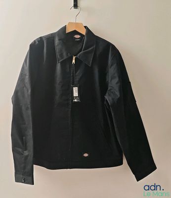 une veste en cuir noir suspendue à un cintre accroché au mur