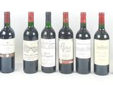 six bottles of wine are lined up in a row on a white surface