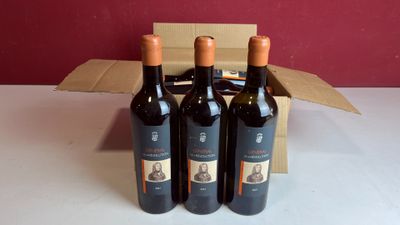 trois bouteilles de vin rouge dans un carton sur une table