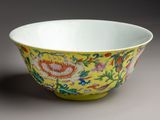 yellow and red bowl with floral designs on it on a gray surface