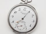 une montre de poche en argent posée sur une surface blanche
