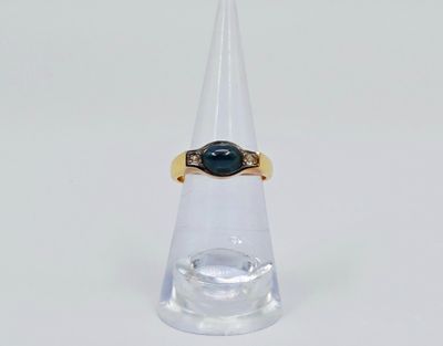 un gros plan d'une bague ornée d'une pierre noire posée au sommet d'un cône transparent