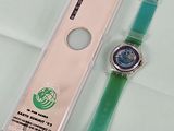 une montre verte posée à côté d'un étui à montre transparent
