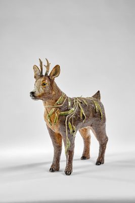 une figurine représentant un cerf debout sur une surface blanche