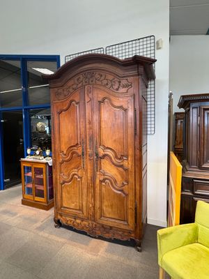 une grande armoire en bois dans une pièce où se trouve une chaise jaune