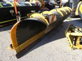yellow and black snow plow sitting on top of a parking lot next to other vehicles