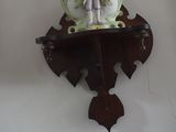 une horloge accrochée au mur, surmontée d'une figurine