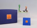 une petite figurine représentant un homme assis devant une cabine bleue