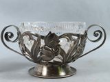 a silver vase with a flower inside of it on a table