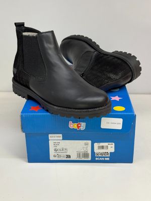 Les bottes noires des enfants sont posées sur une boîte bleue.