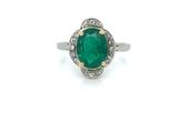 a close up of a ring with a green stone surrounded by diamonds
