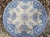 an old blue and white plate sitting on top of a marble counter