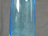 un vase en verre bleu posé sur une surface grise