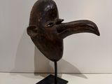 an image of a wooden mask on a stand on a white surface
