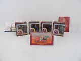 cinq petites boîtes de figurines posées sur une surface blanche