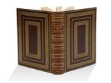 un vieux livre à la couverture brune posé sur une surface blanche