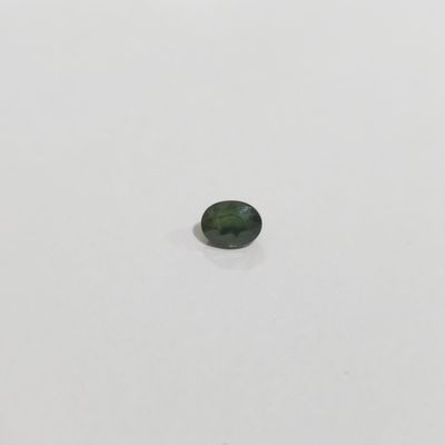 une tourmaline verte posée sur une surface blanche