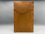une vieille boîte en bois recouverte de cuir marron, posée sur une surface blanche