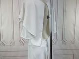 a white dress on a mannequin stand in front of a wall